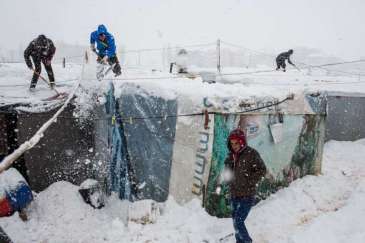 © UNHCR/A.McConnell | Syrian refugees remove snow from their shelters at an informal tented settlement in the Bekaa Valley, Lebanon during a blizzard earlier today.