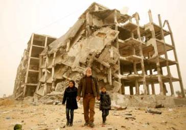 © UNICEF/NYHQ2015-0248/El Baba Ali Hassouna holds the hands of his granddaughters, 11-year-old Samar Barakat (left) and 6-year-old Rosol, near the remnants of the residential towers where the girls used to live, in the city of Beit Lahia, in the northern Gaza Strip, State of Palestine. 