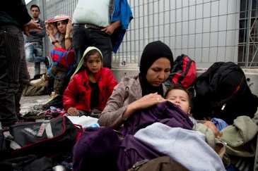 Migrants sleep rough at Mytilene's port until transport is available to take them to a detention centre