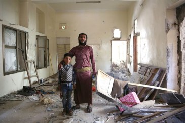Abdallah and his six-year-old son stand in what used to be the entrance of their home, in Sana’a’s Bayt Mayad neighbourhood. Photo: OCHA/Charlotte Cans