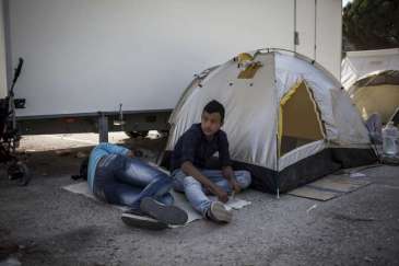 Two boys rest next to their tent outside the screening centre at Moria. Refugees and migrants live in tents until there is space available to accommodate them inside the centre. Photo: UNHCR/S.Baltagiannis