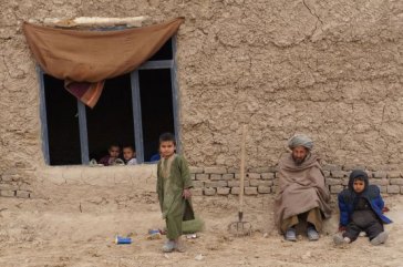 Members of a family sit outside their simple home in northern Afghanistan’s Faryab province. Photo: UNHCR/S. Sisomsack