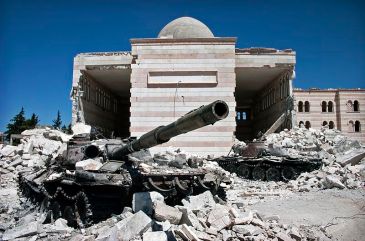 **Photo: Two destroyed tanks in front of a mosque in Azaz, Syria. From March 6 to July 23, a battle between the Free Syrian Army (FSA) and the Syrian government was fought for control over the city of Azaz, north of Aleppo, during the Syrian civil war | Author: Christiaan Triebert | Source: Flickr: Azaz, Syria | Wikimedia Commons