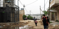 children walk past qafisheh checkpoint on a muddy road on their way home from school in hebron's tel rumeida neighborhood on 2 may 2019. (photo_ ivan karakashian_nrc)